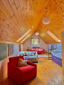 a living room with a red couch and two beds at Domek na końcu świata in Szymbark