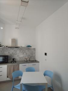 uma cozinha com uma mesa e cadeiras azuis em LA REGGIA APARTMENTS MILAZZO em Milazzo