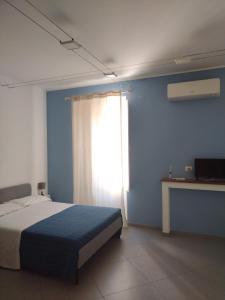 1 dormitorio con 1 cama con pared azul y ventana en LA REGGIA APARTMENTS MILAZZO en Milazzo