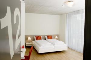 a white bedroom with a bed and a window at Gästehaus Hunziker in Zurich