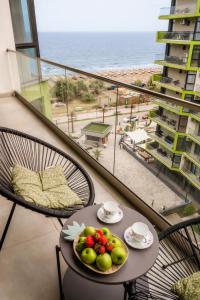 uma mesa com frutas numa varanda com vista para a praia em Andreas - Pool & Spa Beach Resort em Mamaia Nord – Năvodari