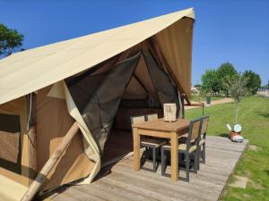 une tente avec une table et des chaises sur une terrasse dans l'établissement Tente Lodge pour 5 personnes en bordure de la rivière Allier, à Saint-Yorre