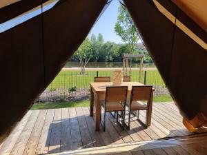 einen Holztisch und Stühle auf einer Holzterrasse in der Unterkunft Tente Lodge pour 5 personnes en bordure de la rivière Allier in Saint-Yorre