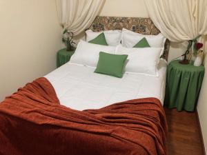 uma cama grande com lençóis brancos e almofadas verdes em Casa da Corticeira em Caminha