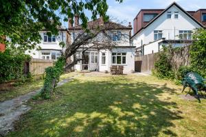 ein Haus mit einem Hof mit einem Zaun in der Unterkunft Lovely garden apartment in Wimbledon Town Centre with private parking by Wimbledon Holiday Lets in London