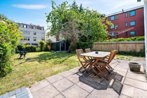 een patio met een tafel en stoelen in een tuin bij Lovely garden apartment in Wimbledon Town Centre with private parking by Wimbledon Holiday Lets in Londen