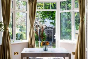 una habitación con ventanas y una mesa con flores. en Lovely garden apartment in Wimbledon Town Centre with private parking by Wimbledon Holiday Lets, en Londres
