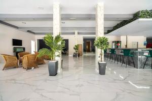 a lobby with tables and chairs and potted plants at Sotirakis Hotel in Faliraki