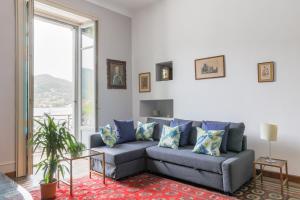 ein Wohnzimmer mit einem grauen Sofa und einem großen Fenster in der Unterkunft Easylife - Elegante Dimora sul lago di Como in Como