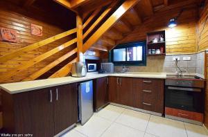 cocina con armarios marrones y techo de madera en Villa Joe en Peqi‘in H̱adasha