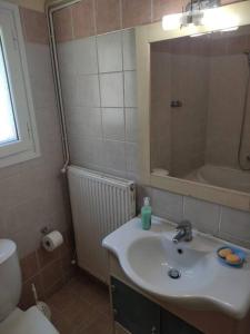 bagno con lavandino, servizi igienici e specchio di Blue and white apartments 3 a Benitses