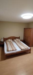 - une chambre avec un grand lit et une tête de lit en bois dans l'établissement Rózsakert Apartmanház, à Hajdúszoboszló