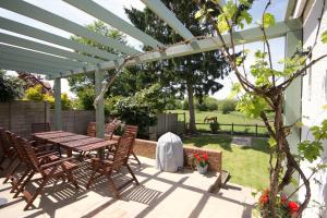 a patio with a table and chairs under a white pergola at Avondale New Forest in Godshill