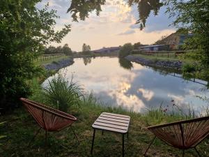 two chairs and a table next to a river at Gîte domaine de la galopade in Étréaupont