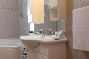 a white bathroom with a sink and a tub at Apartments Vranjić in Trogir +45 photos