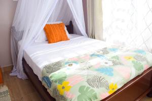 a bed with a comforter with an orange pillow on it at Ilala House, Voi - 2 bed, 2 bath in Voi