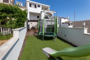 a small yard with a playground on the side of a house at Apartments Vranjić in Trogir