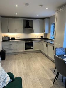 a kitchen with white cabinets and a table and chairs at seaview 87 in Portrush