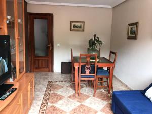 a dining room with a table and chairs and a tv at APARTAMENTO MEDIODIA in Luanco