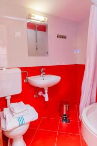 een rode badkamer met een toilet en een wastafel bij Apartments Mikulić in Rogoznica