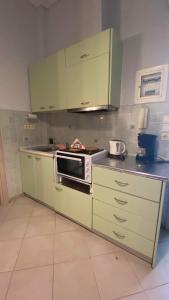 a kitchen with green cabinets and a microwave at cozy minimal apartment in Piraeus