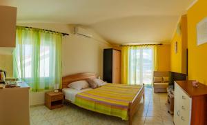 1 dormitorio con cama, paredes y ventanas de color amarillo en Apartments Mikulić en Rogoznica