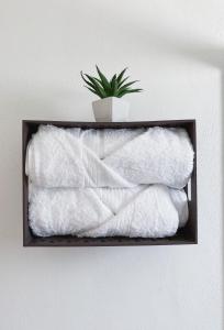a shelf with white towels and a potted plant at Hermoso depto con alberca en el condo La Luminaria Casonas y Villas in San Miguel de Allende