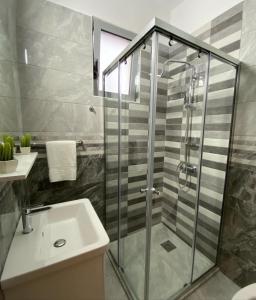 烏爾齊尼的住宿－Robi Apartments，一间带玻璃淋浴和水槽的浴室