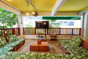 Local Hostel Manaus في ماناوس: غرفة معيشة مع أرائك وتلفزيون على شرفة
