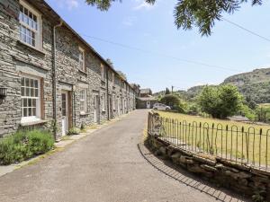 a stone house with a fence next to a road at Slaters Rest in Chapel Stile