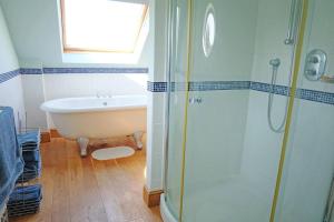 a bathroom with a bath tub and a shower at A stunning converted barn offering country life. in Chewton Mendip