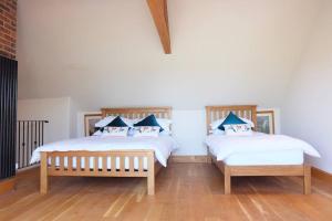 two beds in a room with white walls and wooden floors at A stunning converted barn offering country life. in Chewton Mendip