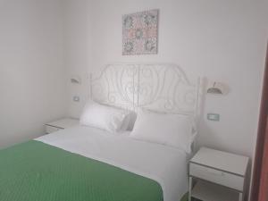 - un lit blanc avec une tête de lit blanche et une couverture verte dans l'établissement Agriturismo Valle Dei Gelsi, à Peschici