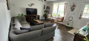 a living room with a couch and a tv at Boho Cottage - Hot tub and close to Beach in Fort Erie
