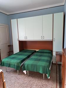 een slaapkamer met een groen bed en witte kasten bij La casa Dei Dadi in Milazzo