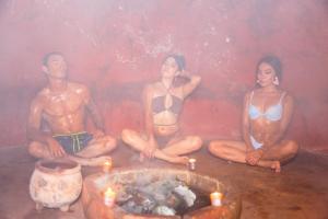 uma pintura de três pessoas sentadas em torno de uma banheira em Uxmal Resort Maya em Uxmal