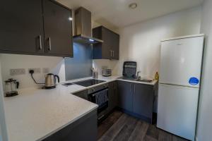a kitchen with a white refrigerator and wooden floors at Captivating 1-Bed apartment Merthyr Tydfil - in Merthyr Tydfil