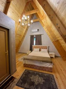 a bedroom with a bed in an attic with a chandelier at Qafqaz house in Gabala