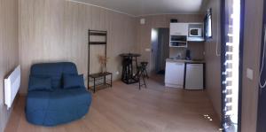 ein Wohnzimmer mit einem blauen Stuhl und eine Küche in der Unterkunft Studio en bois à 20mn du Puy du Fou avec grand jardin in Saint-Mesmin