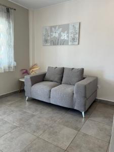 a gray couch in a living room with a tile floor at House Kohili in Nea Vrasna