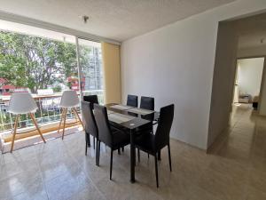 une salle à manger avec une table, des chaises et une grande fenêtre dans l'établissement Mi hogar - Apartamento familiar en Bucaramanga, à Bucaramanga