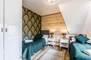 two beds in a small room with a desk and a bed sidx sidx sidx sidx at Apartamenty Tradycja in Zakopane