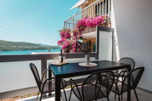 a black table and chairs on a balcony with flowers at Ankica & Anamarija Apartments in Neum