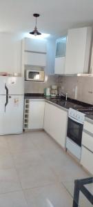 une cuisine avec des armoires blanches et un réfrigérateur blanc dans l'établissement Das thomy, à Córdoba