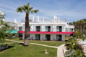 a white building with a palm tree in the yard at Bayside Salgados in Albufeira