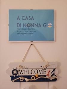 un panneau suspendu sur un mur avec un panneau de bienvenue dans l'établissement A casa di Nonna Giò, à Palerme