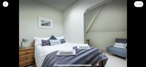 a bedroom with a bed and a blue chair at Ambrose Apartments in Cheltenham