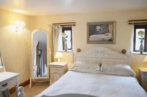 Schlafzimmer mit einem weißen Bett und einem Spiegel in der Unterkunft Bothy in Alston