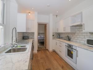 a kitchen with white cabinets and a sink at The Priory in Torquay