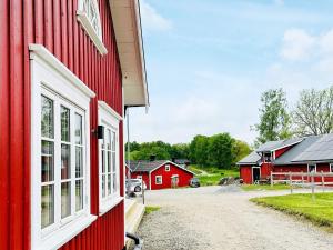 a red barn with white windows and a dirt road at Holiday home ALLINGSÅS, SVERIGE II in Hjälmared